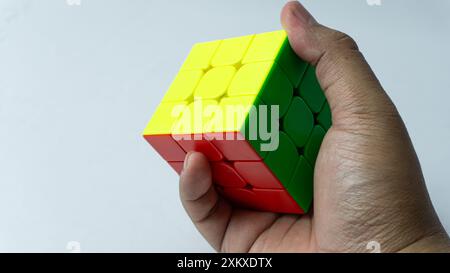 Farbenfrohe, abgeschlossene Lösung des 3x3-Würfels wird isoliert auf weißem Hintergrund in der Hand gehalten Stockfoto