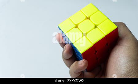 Farbenfrohe, abgeschlossene Lösung des 3x3-Würfels wird isoliert auf weißem Hintergrund in der Hand gehalten Stockfoto