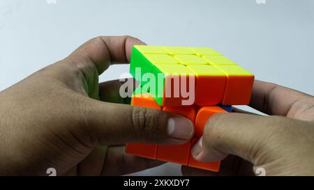 Farbenfrohe, abgeschlossene Lösung des 3x3-Würfels wird isoliert auf weißem Hintergrund in der Hand gehalten Stockfoto