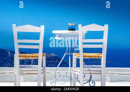 Zwei Stühle und ein kleiner Tisch mit einer wunderbaren Aussicht auf Santorin, Griechenland Stockfoto
