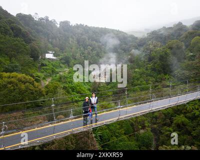 Touristen auf der Seilhängebrücke mit Blick auf den Wald und das Misty Valley aus der Vogelperspektive Stockfoto