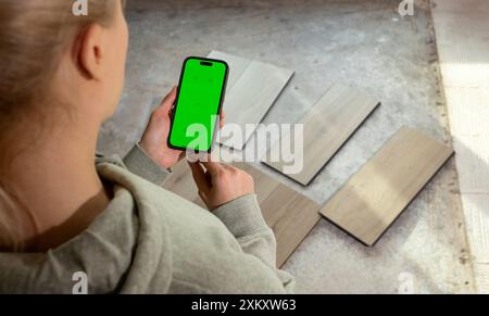 Innenarchitektur Haltevorrichtung mit grünem Chroma-Bildschirm über luxuriösen Vinyl-Holzproben, Laminat auf dem Boden im Haus. Auswählen, Auswählen Stockfoto