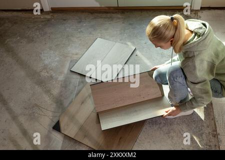 Innenarchitektin Hält Luxuriöse Vinyl Holzproben Auf Betonboden In Der Wohnung. Auswahl Von Wasserdichter Bodenbelag. Heimrekonstruktion. Vinylfliesen Stockfoto