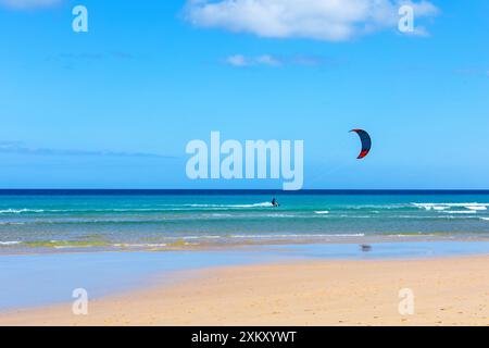 Person, die am Strand Parasailing, die Aussicht von oben genießt. Parasailer gleitet über den Sandstrand mit farbenfrohem Fallschirm Stockfoto