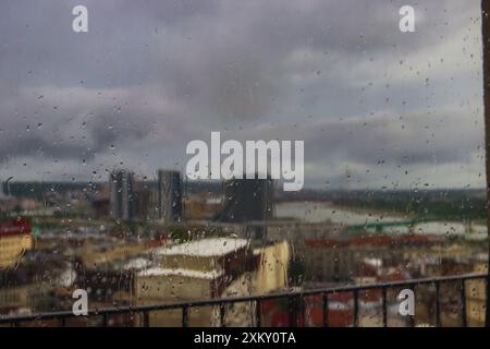 Der Blick auf Belgrad von zu Hause aus durch ein von Regentropfen gewaschenes altes Holzfenster bietet an einem regnerischen Tag eine charmante und nostalgische Stadtlandschaft Stockfoto