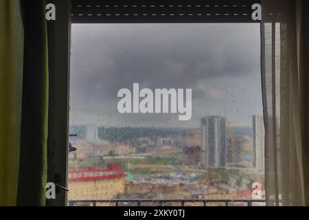 Der Blick auf Belgrad von zu Hause aus durch ein von Regentropfen gewaschenes altes Holzfenster bietet an einem regnerischen Tag eine charmante und nostalgische Stadtlandschaft Stockfoto