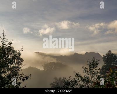 Einige Nebel bedeckt die Berge und Farmen bei Sonnenaufgang, in den östlichen Andengebirgen in Zentral-Kolumbien. Stockfoto