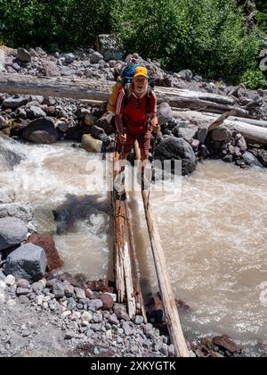 WA25542-00...WASHINGTON - PCT-Wanderer über den Kennedy Creek in der Glacier Peak Wilderness. Stockfoto