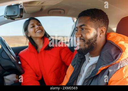 Wunderschönes, glückliches junges, liebevolles Paar, das Hände hält und lächelt, während er in seinem ersten Auto sitzt. Kaufen Sie Ihr erstes Fahrzeugkonzept Stockfoto