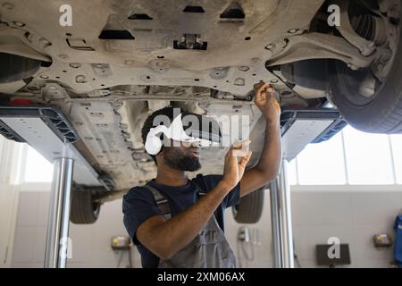 Mechaniker, der virtuelle Realität für die Fahrzeugkontrolle in der Garage nutzt Stockfoto