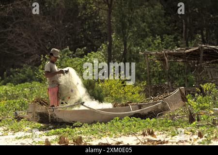 Ein Subsistenzfischer, der sein Fischernetz am Strand von Tarimbang in Tabung, East Sumba, East Nusa Tenggara, Indonesien, abrollt. Stockfoto