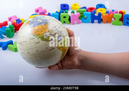 Kleines Modell gobe in Hand mit bunten Buchstaben hinter Stockfoto