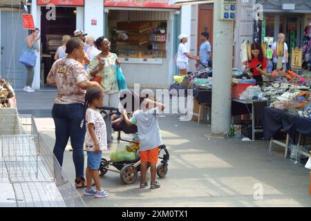Parma, Italien 24. Juli 2024 Eine Familie schlendert an einem sonnigen Tag durch einen belebten Straßenmarkt und kauft verschiedene Waren von Händlern ein Stockfoto