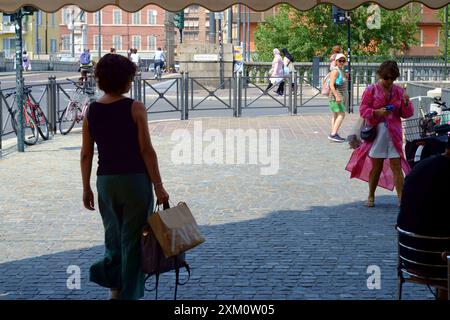 Parma, Italien 24. Juli 2024 Frauen, die an einem sonnigen Tag im Stadtzentrum spazieren, mit Fahrrädern in der Nähe und anderen Personen im Hintergrund Stockfoto