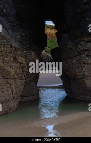 Natürlicher Felsbogen über dem Ozean bei Sonnenuntergang mit ruhiger Atmosphäre und geologischem Wunderkonzept. Cathedral Beach, Lugo, Spanien Stockfoto