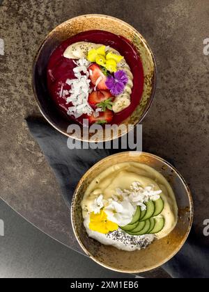 Farbenfrohe Smoothie-Schüsseln, die wunderschön mit Früchten, Nüssen und essbaren Blumen dekoriert sind. Draufsicht Stockfoto