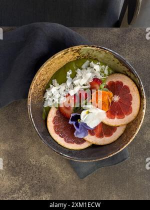 Matcha Smoothie Schüssel mit Orangen-, Erdbeeren- und Kokosflocken, wunderschön dekoriert. Stockfoto