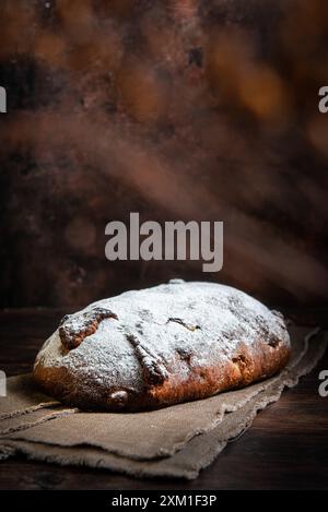 Frisches Sauerteigbrot mit Früchten und Nüssen auf einem Schneidebrett. Stockfoto