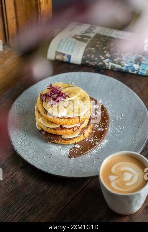Hausgemachter, flauschiger Bananenpfannkuchen mit Schokolade auf einem Coffee-Shop-Tisch. Stockfoto