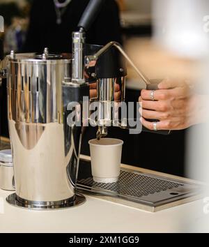 Männliche Hände gießen Milch und bereiten frischen Cappuccino zu. Kaffeekünstler. Stockfoto