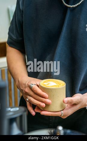 Ein Mann, der eine Tasse Kaffee in einem Café hält. Stockfoto