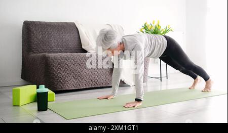 Ältere Frau Mit Grauem Haar, Die Zu Hause Aktiv Yoga-Übungen Macht Stockfoto