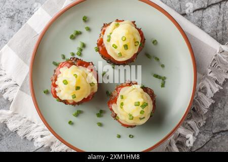 Fingerfood Fleischbällchen Cupcakes mit Tomatensauce und Kartoffelpüree in Nahaufnahme auf einem Teller auf dem Tisch. Horizontale Draufsicht von oben Stockfoto