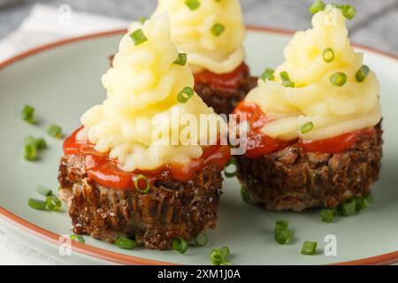 Fingerfood Fleischbällchen Cupcakes mit Tomatensauce und Kartoffelpüree in Nahaufnahme auf einem Teller auf dem Tisch. Horizontal Stockfoto