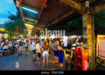 Menschen stehen an Imbissständen, dem Lebensmittelmarkt Nocny Market (Nachtmarkt) auf den ehemaligen Bahnsteigen des Bahnhofs in Warschau, Polen Stockfoto