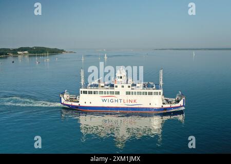 Die Fähre zur Isle of Wight fährt von Yarmouth nach Lymington in der frühen Morgensonne auf einem flachen, ruhigen Meer mit Passagieren an Deck, die sich sonnen. Stockfoto