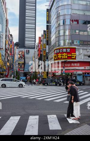 Tokio, Japan - 14. Juni 2024: Zwei junge Erwachsene küssen sich an einem Samstagmorgen an der berühmten Kreuzung der Godzilla Street, während die Stadt das macht Stockfoto