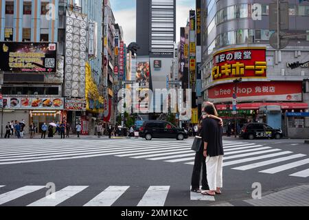 Tokio, Japan - 14. Juni 2024: Zwei junge Erwachsene küssen sich an einem Samstagmorgen an der berühmten Kreuzung der Godzilla Street, während die Stadt das macht Stockfoto