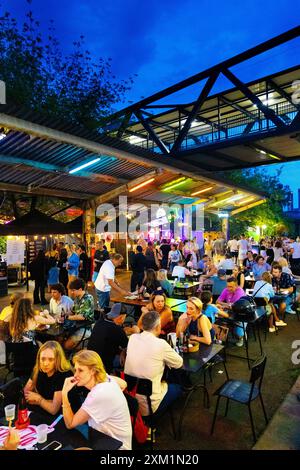 Menschen essen auf dem Open-Air-Markt Nocny Market (Nachtmarkt) auf den ehemaligen Bahnsteigen des Hauptbahnhofs in Warschau, Polen Stockfoto