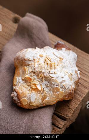 Frisch gebackenes Mandelcroissant mit Nüssen auf einem Holztisch. Draufsicht Stockfoto