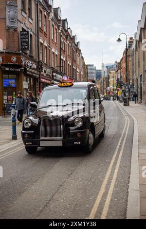 Glänzendes schwarzes Taxi in einer engen Straße. Stockfoto