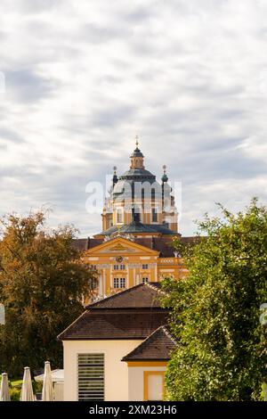 Melk, Österreich - 25. Oktober 2023 : Ein gelbes Gebäude mit einer Kuppel in Melk, Österreich, umgeben von Bäumen und bewölktem Himmel. Stockfoto