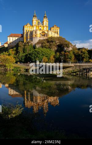 Melk, Österreich - 25. Oktober 2023 : auf einer Klippe in Melk, Österreich, befindet sich Ein gelb-weißes Gebäude, das sich im stillen Wasser spiegelt. Stockfoto