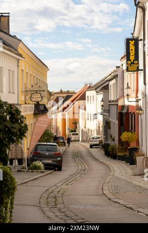 Melk, Österreich - 25. Oktober 2023 : Eine enge Kopfsteinpflasterstraße in Melk, Österreich, gesäumt von bunten Gebäuden. Stockfoto