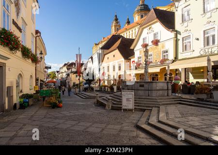 Melk, Österreich - 25. Oktober 2023 : Kopfsteinpflasterstraßen und ein Brunnen mit einer Statue in der Stadt Melk, Österreich. Stockfoto