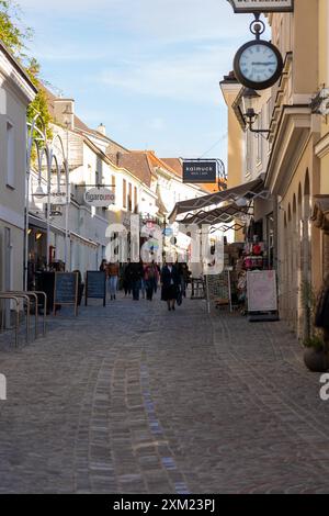 Melk, Österreich - 25. Oktober 2023 : Eine kopfsteingepflasterte Straße in Melk, Österreich, gesäumt von Gebäuden und Geschäften, an denen Menschen vorbeilaufen. Stockfoto