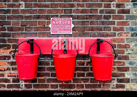 3 alte Feuereimer hängen an einer Backsteinmauer am Bahnhof Sheringham, Teil der restaurierten alten Poppy Line Stationen, N Norfolk Railway Stockfoto