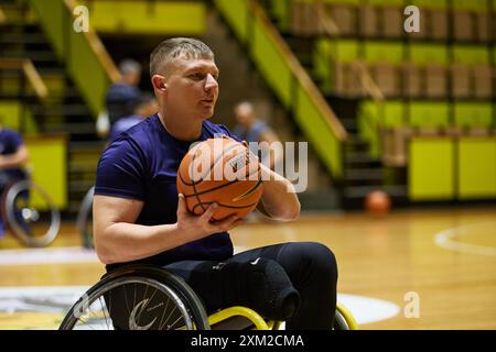 Basketballspieler mit amputiertem Bein spielt adaptives Spiel im Rollstuhl. Kiew - 12. Dezember 2023 Stockfoto