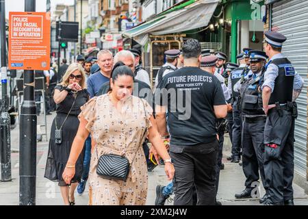 London, Großbritannien. Juli 2024. MET Polizeibeamte benutzen einen Überwachungswagen, um ein Live-Gesichtserkennungsnetz durchzuführen, um Personen zu finden, die von der Polizei und/oder den Gerichten gesucht werden, an der Edgeware Road, London. Auf dem Schild steht, dass Sie nicht durch gehen müssen, und die Anwesenheit so vieler Polizisten bedeutet, dass jeder Täter sich gut in Sicherheit halten würde. Guy Bell/Alamy Live News Stockfoto