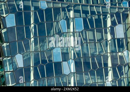 Abstrakte Glasfassade mit Wabenmuster und reflektierenden Mustern auf modernem Gebäude. Stockfoto