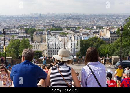 Paris, Frankreich 07.24.2024. Touristen sitzen auf den Stufen vor der Sacre Coeur und bewundern die Aussicht auf Paris Stockfoto