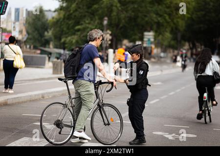 Ein Polizist scannt den qr-Code eines Radfahrers an einem der Eingänge zum Sicherheitsbereich während der Vorbereitungen für die Eröffnung der Olympischen Spiele in Paris. Nur wenige Tage vor der beispiellosen Eröffnung der Olympischen Spiele in Paris, die auf sechs Kilometern der seine stattfinden werden, verändert sich die Stadt des Lichts. Um den sehr eingeschränkten Bereich des Bereichs, in dem die Eröffnungszeremonie stattfindet, wurden Geländer aufgestellt, sodass Sie völlig leere Straßen sowie Terrassen von Cafés und Restaurants sehen können. (Foto: Telmo Pinto/SOPA Images/SIPA USA) Stockfoto