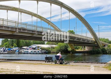 Ein Mann mittleren Alters fischt an einem sonnigen Sommertag in der Themse neben der Walton Bridge Surrey England UK Stockfoto