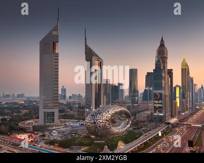 Dubai, Vereinigte Arabische Emirate - Sheikh Zayed Road in einem wunderschönen Sonnenuntergang mit Emirates Twin Towers und Museum of the Future und verkehrsreichen Straßen Stockfoto