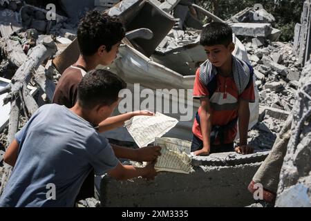Khan Yunis, Palästinensische Gebiete. Juli 2024. Palästinensische Kinder halten zerrissene Seiten des Koran, die zwischen den Überresten eines zerstörten Gebäudes nach einem israelischen Luftangriff auf Khan Younis gefunden wurden. Abed Rahim Khatib/dpa/Alamy Live News Stockfoto