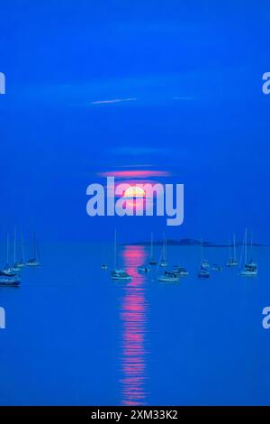 Voller Buck Mond, der im Wasser im Kanal aufsteigt und reflektiert und den Himmel erleuchtet Stockfoto